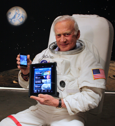Buzz Aldrin in a spacesuit holding an iPad displaying his application
